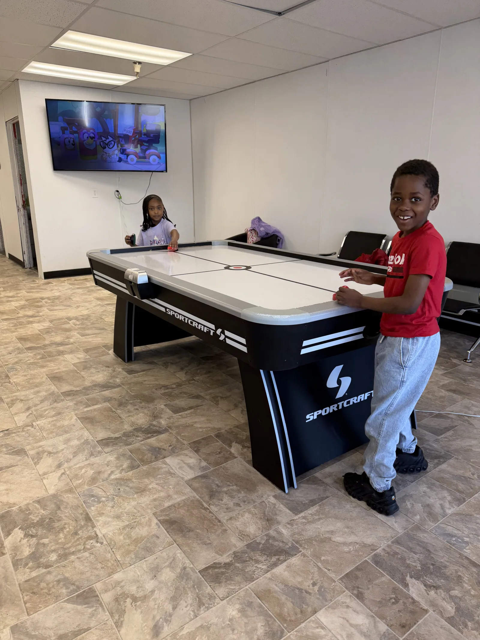 Kids playing air hockey in the Gentleman's Barbershop waiting area