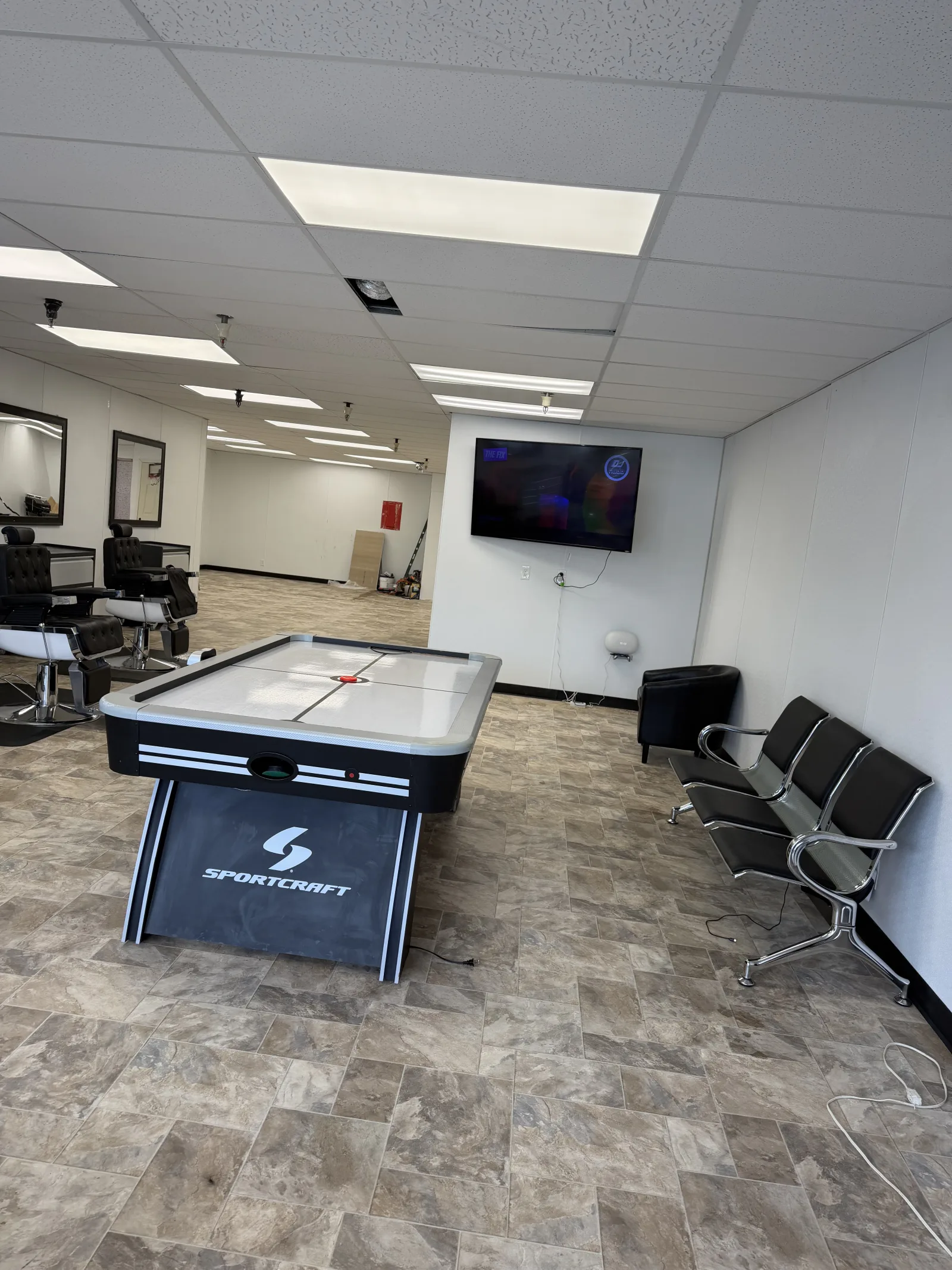 Sportcraft air hockey table in the barbershop lounge with TV and seating